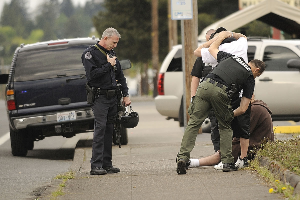 Vancouver Police officers search two men detained on St. Johns Boulevard during a search for an individual in the Rose Village neighborhood.