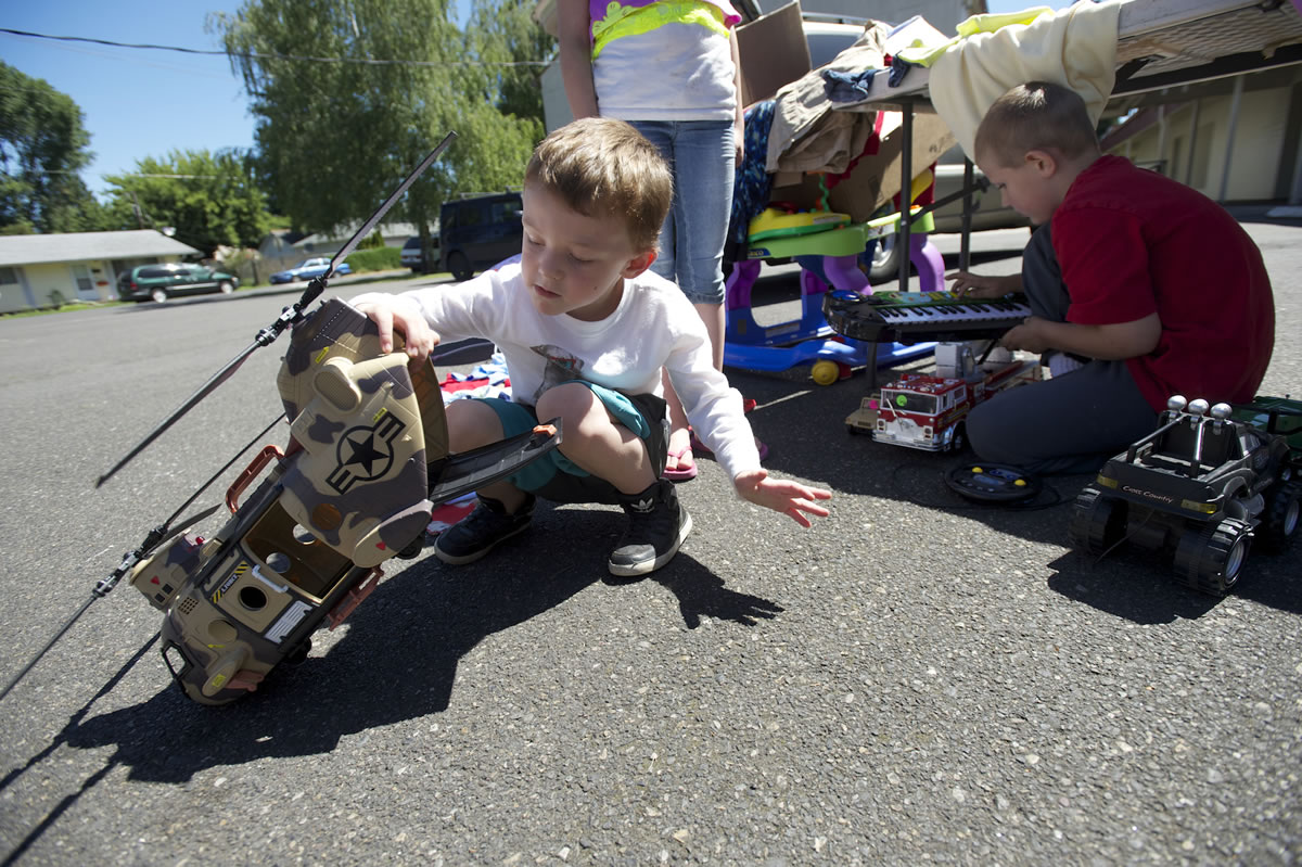 Jake Swan, 4, left, looks at a toy helicopter being sold by Jonathan Arnot, 7, right, during the Rose Village Neighborhood Association's yard sale at Memorial Lutheran Church earlier in June.