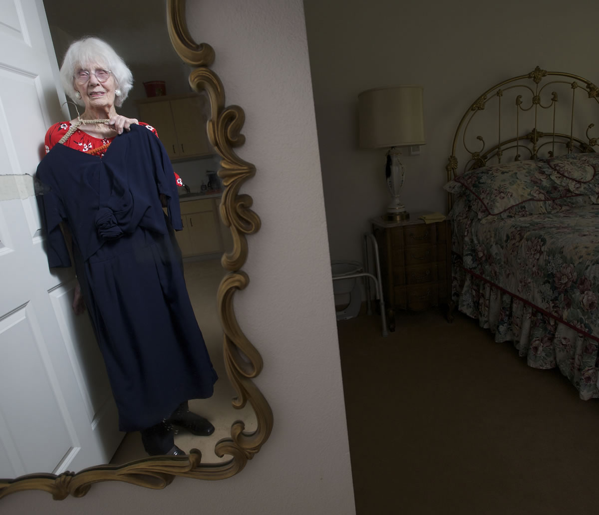 Maude Ryan, 98, holds the navy blue dress that she wore on her 25th wedding anniversary in 1961 at her Orchards home.