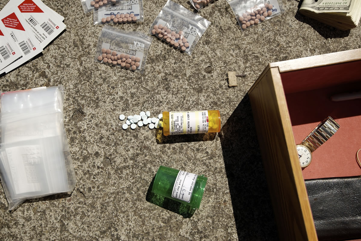 A law enforcement officer with the Clark-Vancouver Regional Drug Task Force finds thousands of dollars' worth of pills during an investigation and drug bust of a suspected drug dealer on July 24.