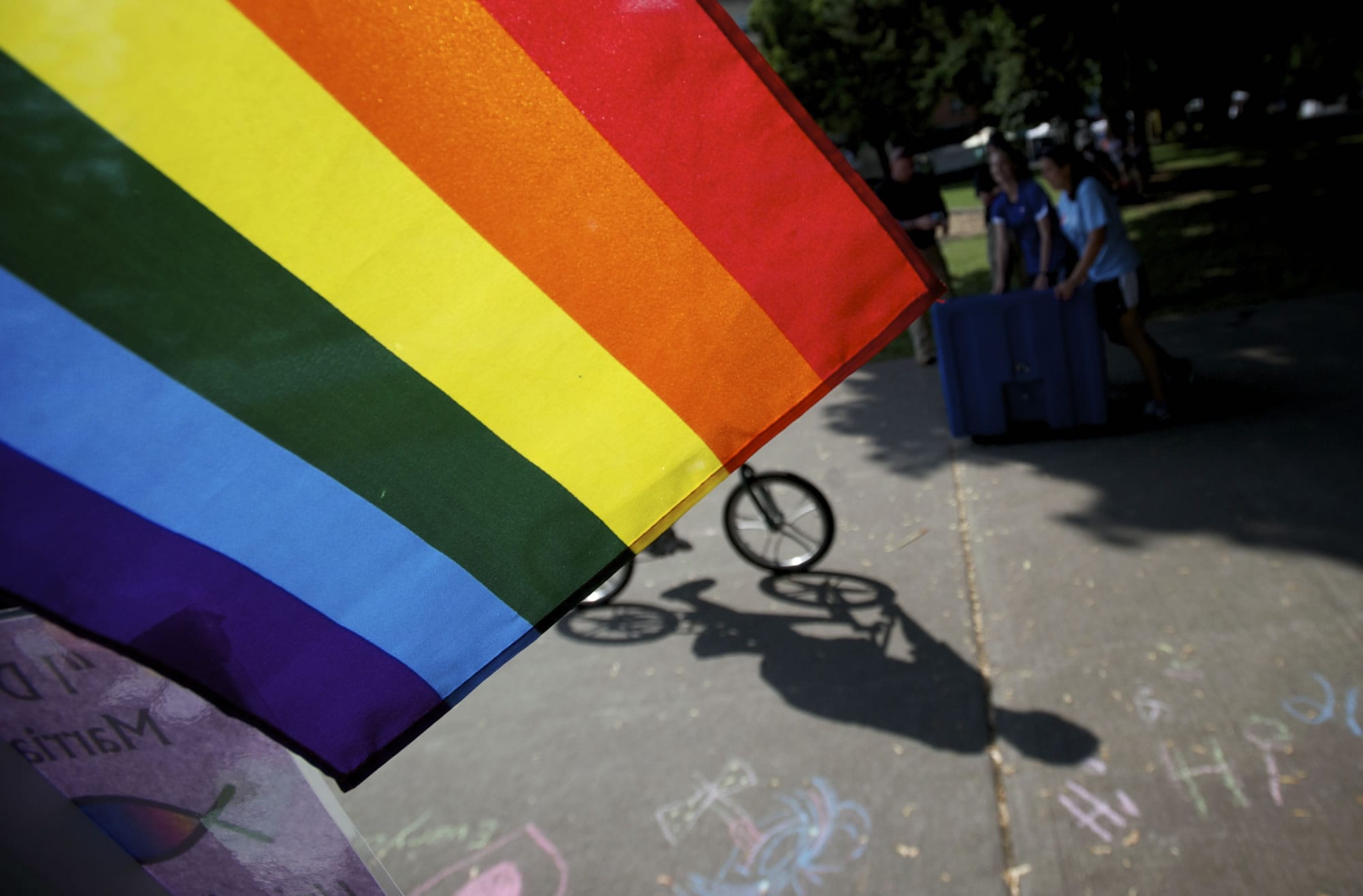 A bicyclist rides past a rainbow flag during the 18th annual Saturday in the Park event celebrating the area's LBGT community.