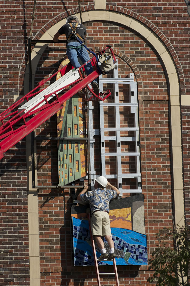 Dave Sams of Advanced Electric Signs, top, and Mike Starks of Soha Signs hang panels of mosaic artwork on the side of VSAA.