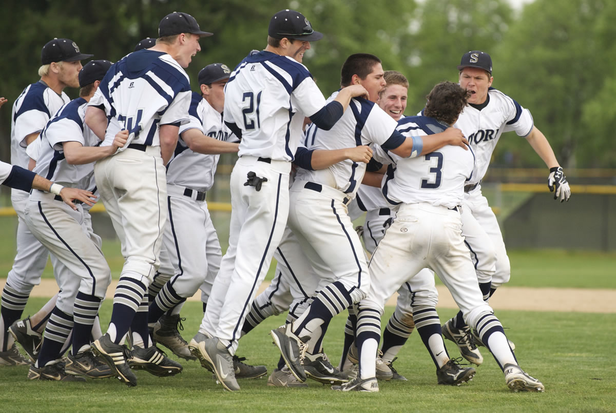 The Skyview baseball team swarms Reiley Henderson (3) after Henderson drove in the winning run in the bottom of the seventh inning as the Storm rallied to beat Heritage 6-4 and win the 4A district championship game Thursday at Propstra Stadium.