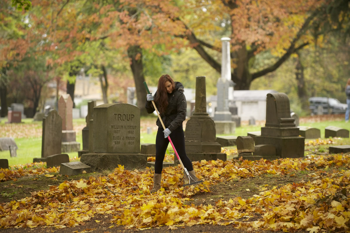 Photos by Steven Lane/The Columbian
Isabella Christner, 14, volunteering with the Fort Vancouver LEO Club, rakes leaves at the Old City Cemetery as part of the Make a Difference Day event Saturday.