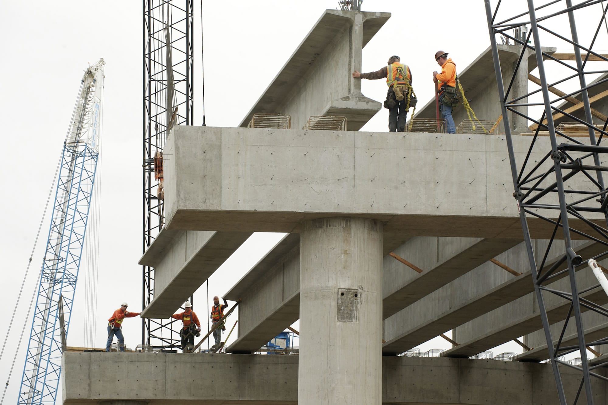 Workers from Max J. Kuney Co. lift a concrete girder onto bridge supports Tuesday as part of the Salmon Creek Interchange Project.