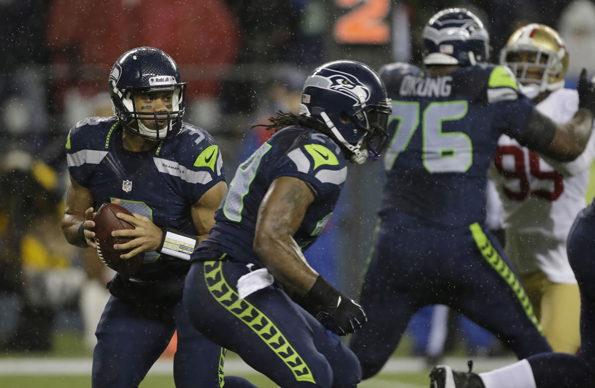 Seattle Seahawks quarterback Russell Wilson, left, looks to pass against the San Francisco 49ers.