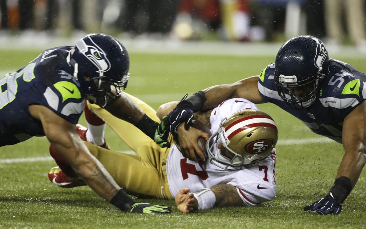 San Francisco 49ers quarterback Colin Kaepernick (7) is tackled by Seattle Seahawks' Bobby Wagner, right, and Leroy Hill, left, in the first half Sunday.