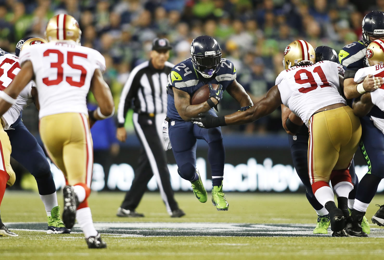 Seattle Seahawks' running back Marshawn Lynch (24) leaps as he carries the ball against San Francisco 49ers' Eric Reid (35) and Ray McDonald (91) in the first half of an NFL football game, Sunday, Sept. 15, 2013, in Seattle.