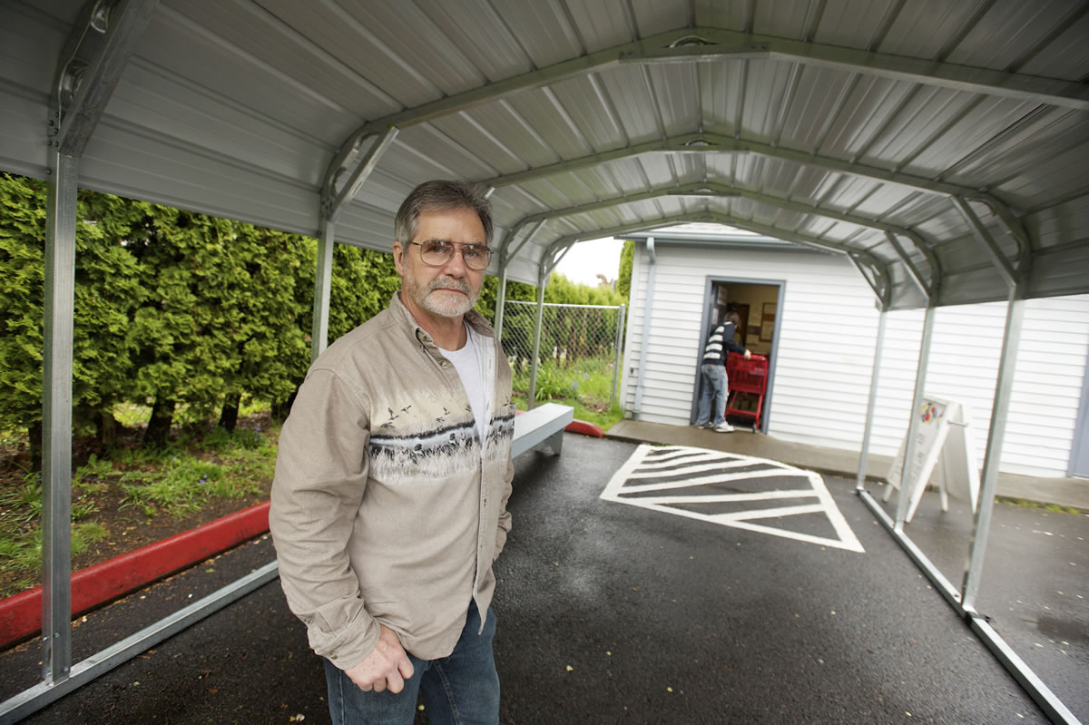 Don Espey, president of F.I.S.H. of Orchards, stands under a new carport that was installed to keep clients dry while they wait outside of the food bank.
