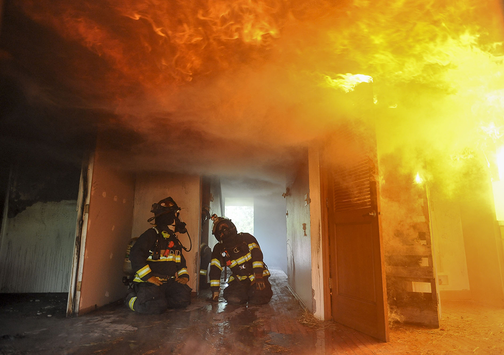 Columbian reporter Emily Gillespie (L) takes part in a fire department training exercise in Camas Tuesday April 21, 2015. The Camas-Washougal Fire Department burnt down a house for training purposes.