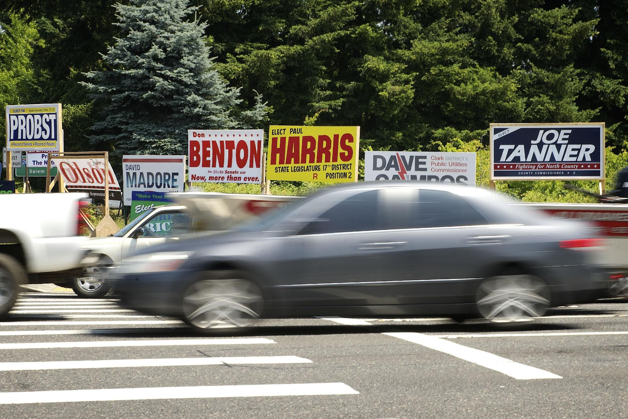 Motorists pass by political campaign signs at Northeast 134th Street and Northeast Highway 99 on Monday.