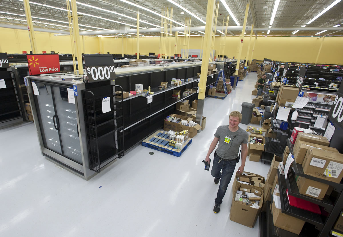 Assistant manager James Carlson walks past as employees stock the shelves of the new Walmart Neighborhood Market, planned to open July 17 at Vancouver Plaza.