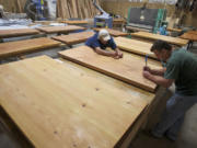 Production supervisor Craig Capistran, right, and carpenter Steve Hasz complete finishing work on an order of custom tables June 29 at Heart of Wood.