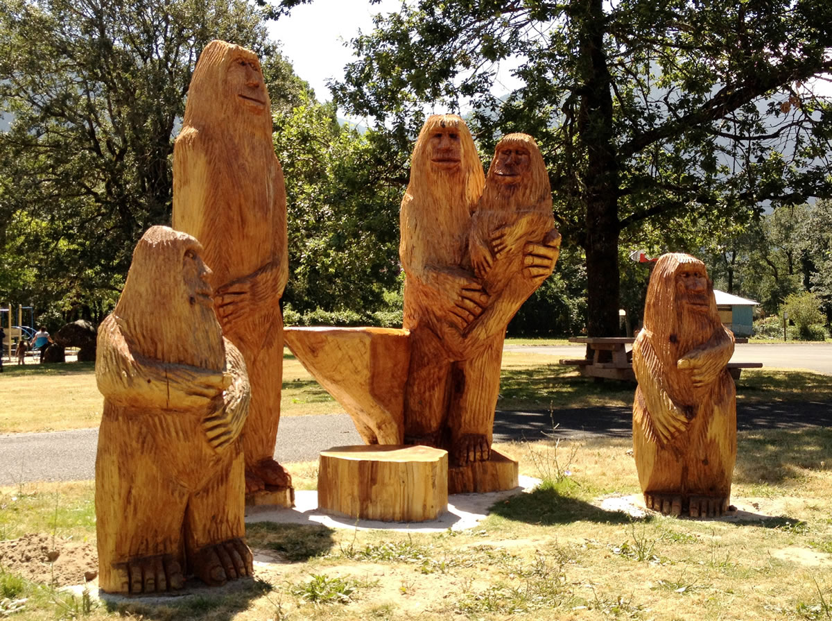 A series of wood-carved Bigfoots stands along a children's train in North Bonneville.