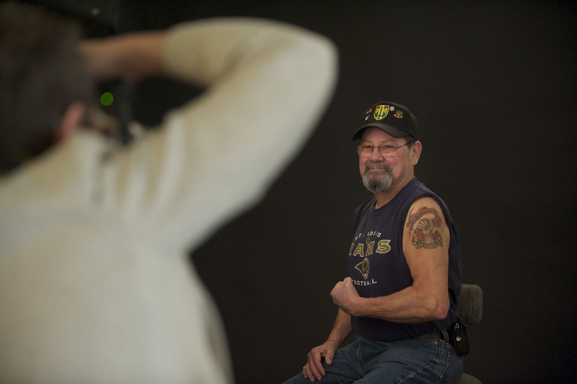 U.S. Army veteran Richard Alvarez flexes as Kate Singh takes a photograph for an exhibit of military-related tattoos.