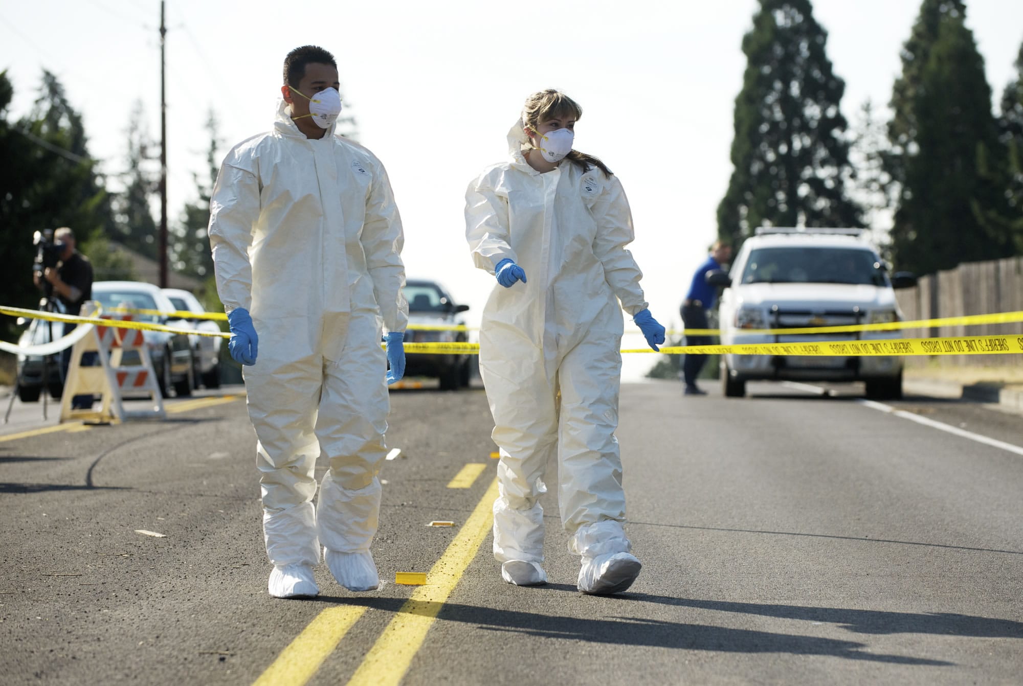 Skills Center student interns Edgar Quintero, 17, left, and Clair Becker, 18, wear protective gear to prepare to search a Dumpster for evidence at a homicide scene in Northeast Hazel Dell on Monday.