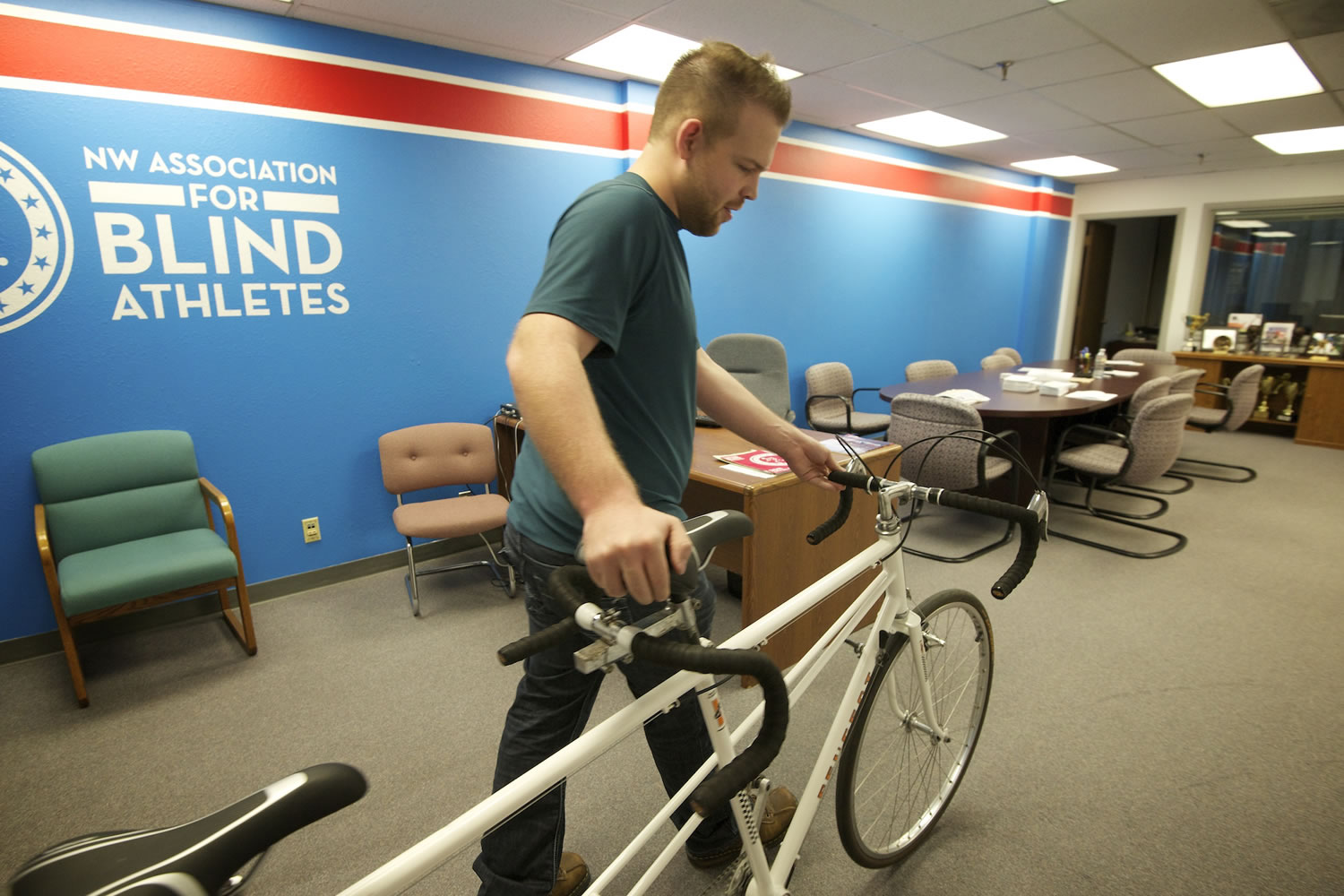 Billy Henry, executive director for Northwest Association for Blind Athletes, walks a tandem bike into the nonprofit's office in Vancouver on Monday.