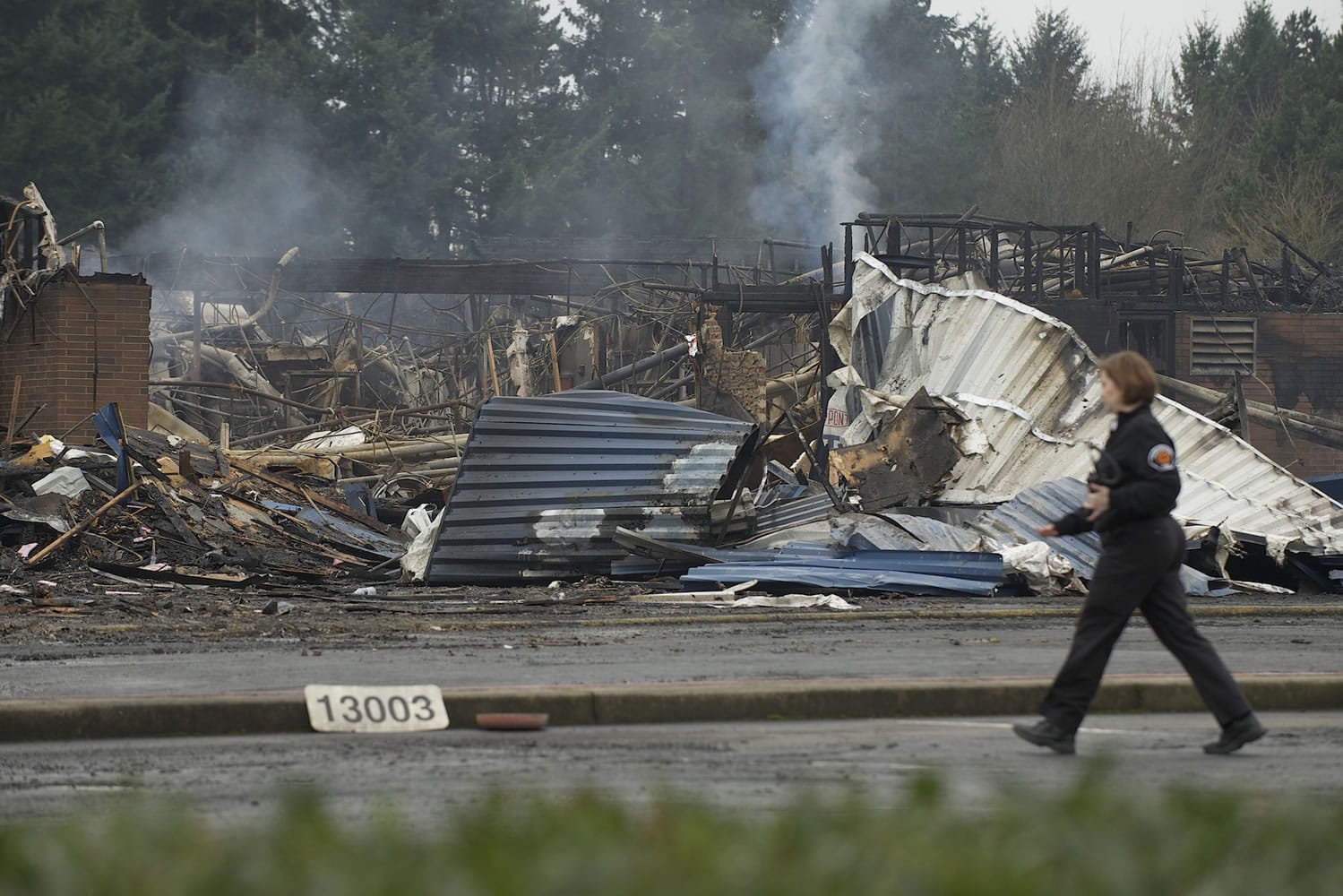 A fire investigator walks past the burned out rubble of Crestline Elementary School on Monday.
