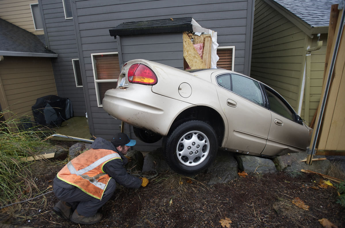 Carlos Urbina of Chuck's Towing of Washougal works to remove a car that crashed Sunday afternoon into this house at 3031 N.W.
