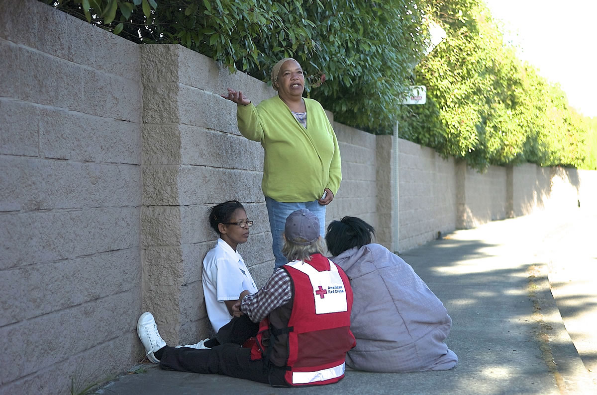 Rhonda Parker, green shirt, talks with Tammy Lacy, left, a Red Cross volunteer, center, and Tatayana Wesley, right, after a early morning fire caused considerable damage to their house Tuesday.