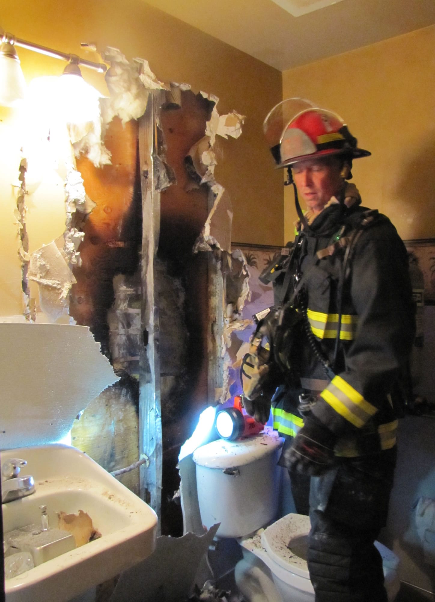 A firefighter inspects damage to a restroom after an electrical fire at Tommy O's Thursday afternoon.