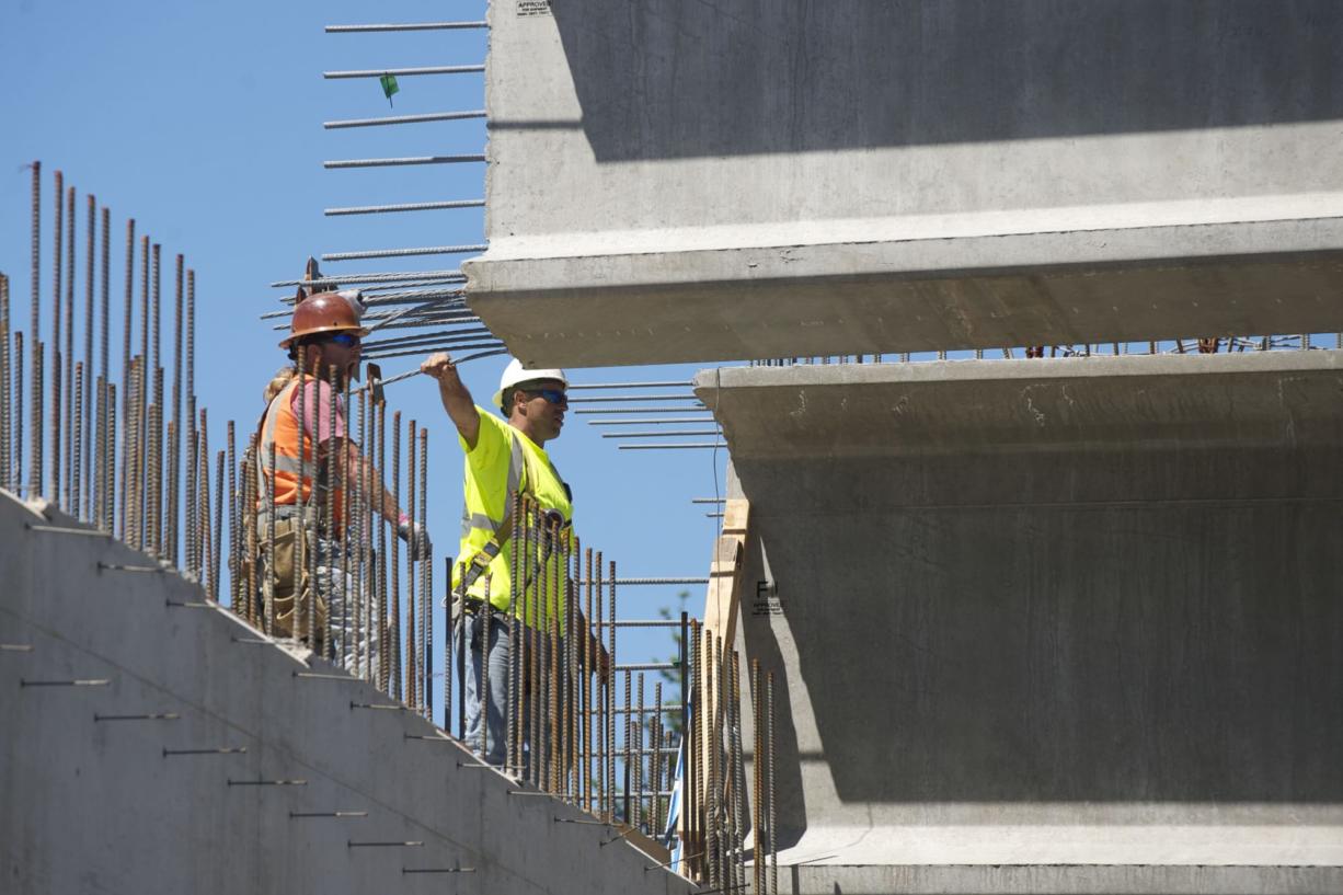 Workers stand atop the skeleton of what will soon form the Northeast 139th Street overpass and guide 175,000-pound girders into place. The work is part of the Salmon Creek Interchange Project, which required both north and south lanes of Interstate 5 be closed Saturday.