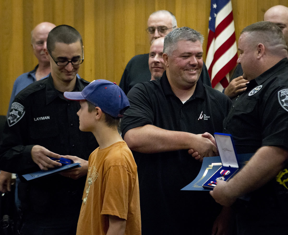 Officers Jesse Layman, left, and Dan McPherson, right, receive Life Saving Medals and a Certificates of Merit for their quick actions that saved the life of Jason Dodge, 36, center, on May 6. Dodge got a chance Monday night to meet the two men for the first time and thank them.