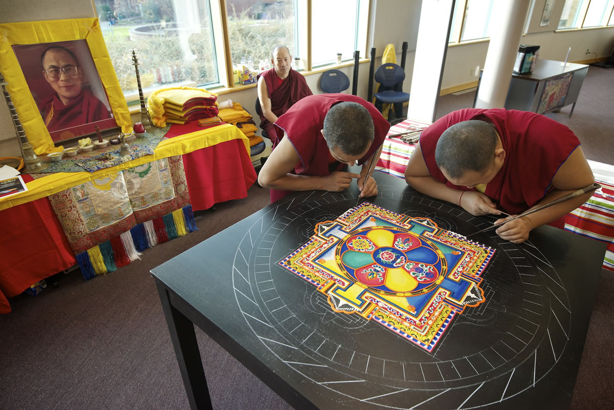 Tibetan monks Lobsang Yeshi, left, and Ngaweng Choegyal use a tiny metal funnel called a &quot;chakpur&quot; Tuesday to create a sand mandala, or sand painting, at Clark College's Cannell Library in Vancouver. A closing ceremony, when the artwork will be destroyed, is set for 3 p.m.