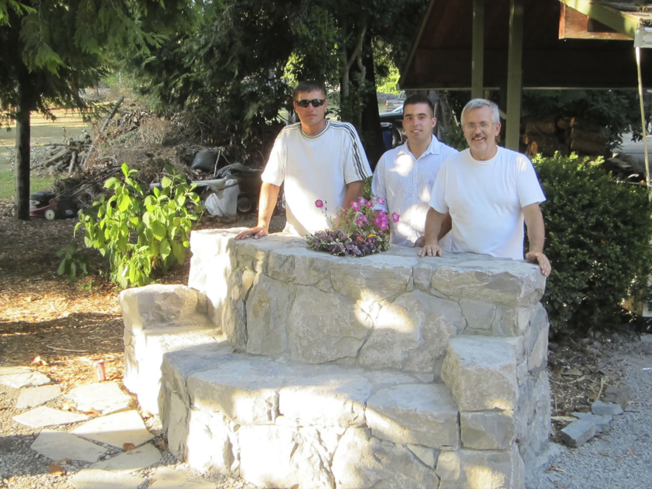 Old Evergreen Highway: Stonemason Alex Igmunov,  from left, Marie's son Steven Day and arboretum manager Kelly Punteney stand near the stone bench memorializing the late Marie Day at the Jane Weber Evergreen Arboretum  in Vancouver.