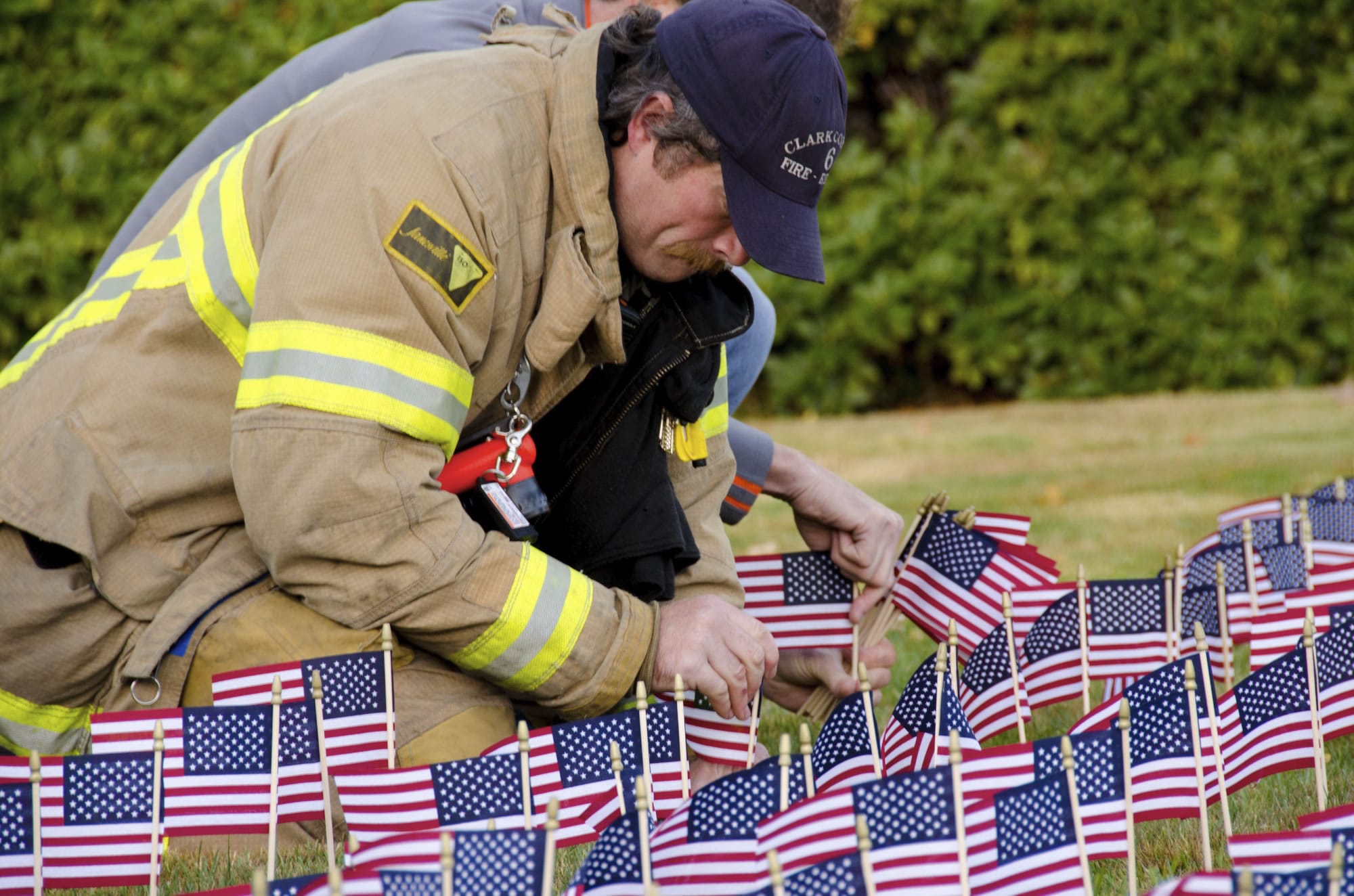 Hazel Dell: Firefighter Casey Taylor places flags in the ground to honor fallen firefighters at the Fire District 6 remembrance ceremony on Sept.