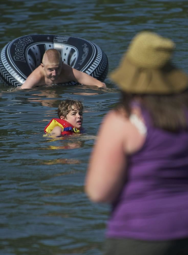 Devyn Thomas, 5, of Vancouver, looks back toward shore at his mother, Diana Thomas, while swimming Friday at Klineline Pond.