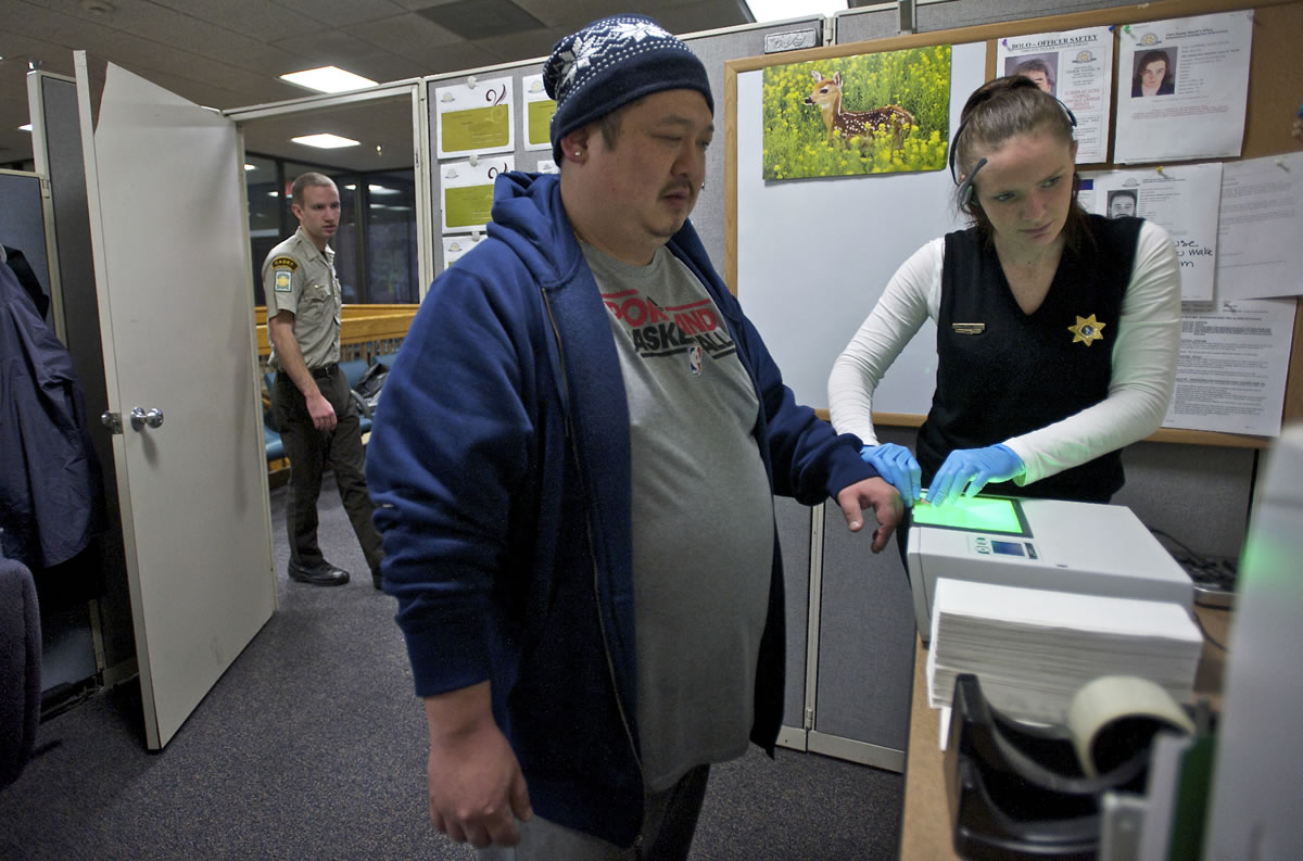 Clark County Sheriff's support specialist Emily Cain takes fingerprints Tuesday from Daniel Kwon, 35, of Vancouver in order to renew his concealed pistol license.