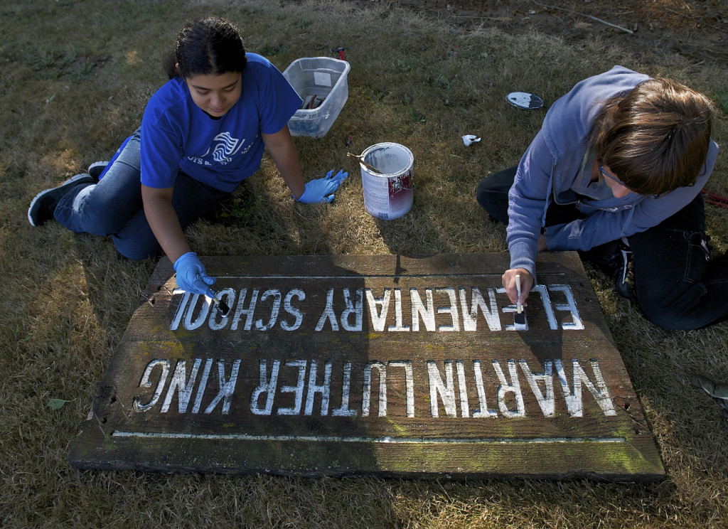 Volunteers Sahara Jones, 12, and Ginger Hemming, 46, re-paint a school sign during a clean up effort at Martin Luther King Elementary School as part of Clark County Connects service day on Saturday.