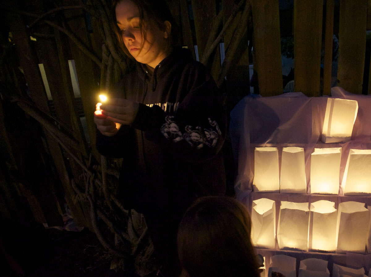Cali Murdock, 21, of Vancouver lights a candle in support of a friend as people gather outside the Vancouver YWCA, offering a moment of silence for those who have died from domestic violence.