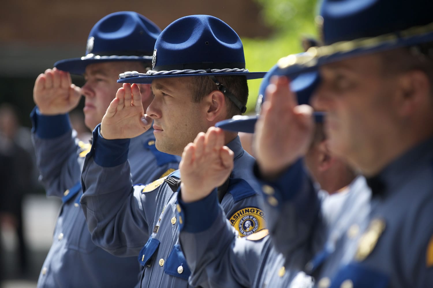 Washington State Patrol troopers salute during the national anthem.