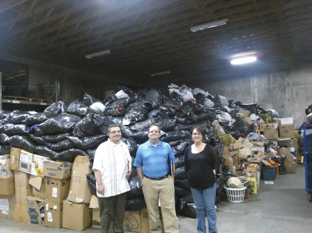 Arc board members Mike Dalesandro, from left, and John Weber and staffer Wendy Kness show off 50,000 pounds of clothing donations.