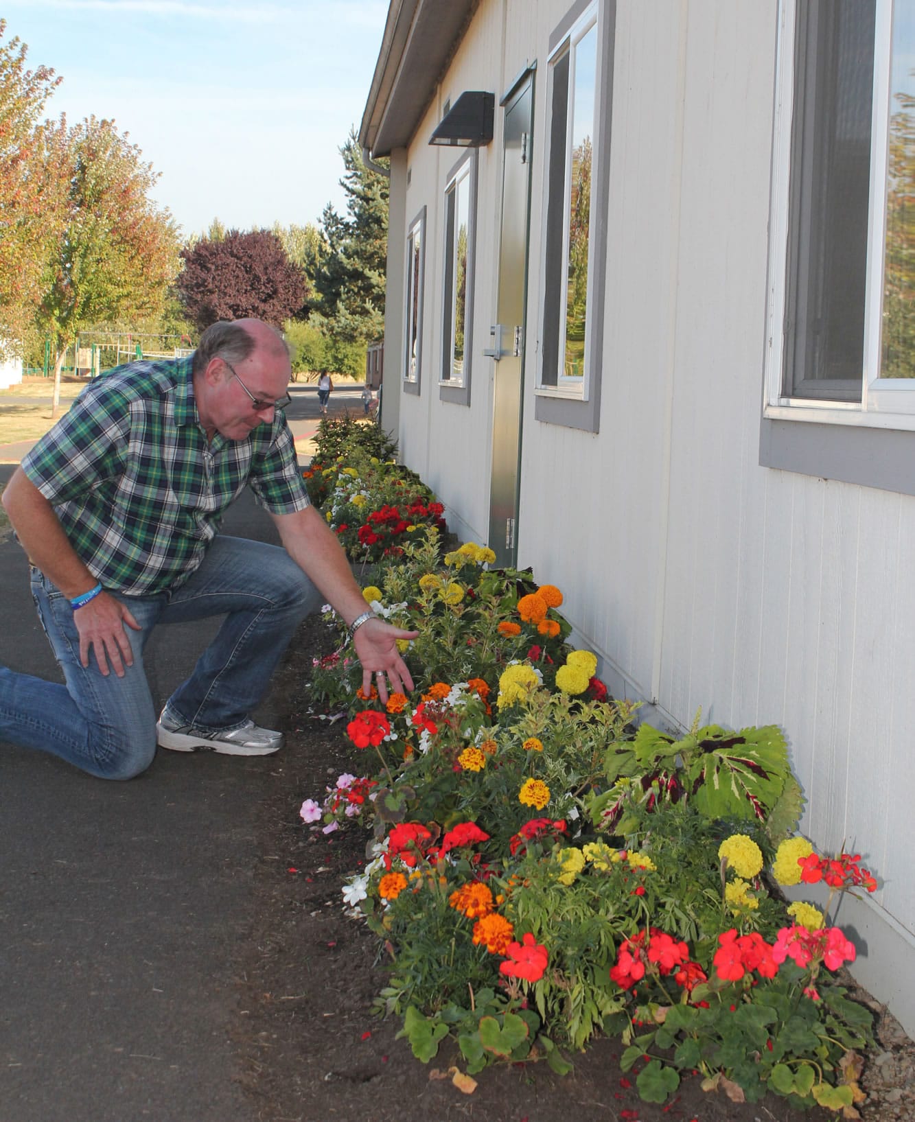 Battle Ground: River HomeLink principal Mark Clements is on his knees with admiration for the flowers that were donated to his expanding program by Chapmanis Greenhouse and Nursery.
