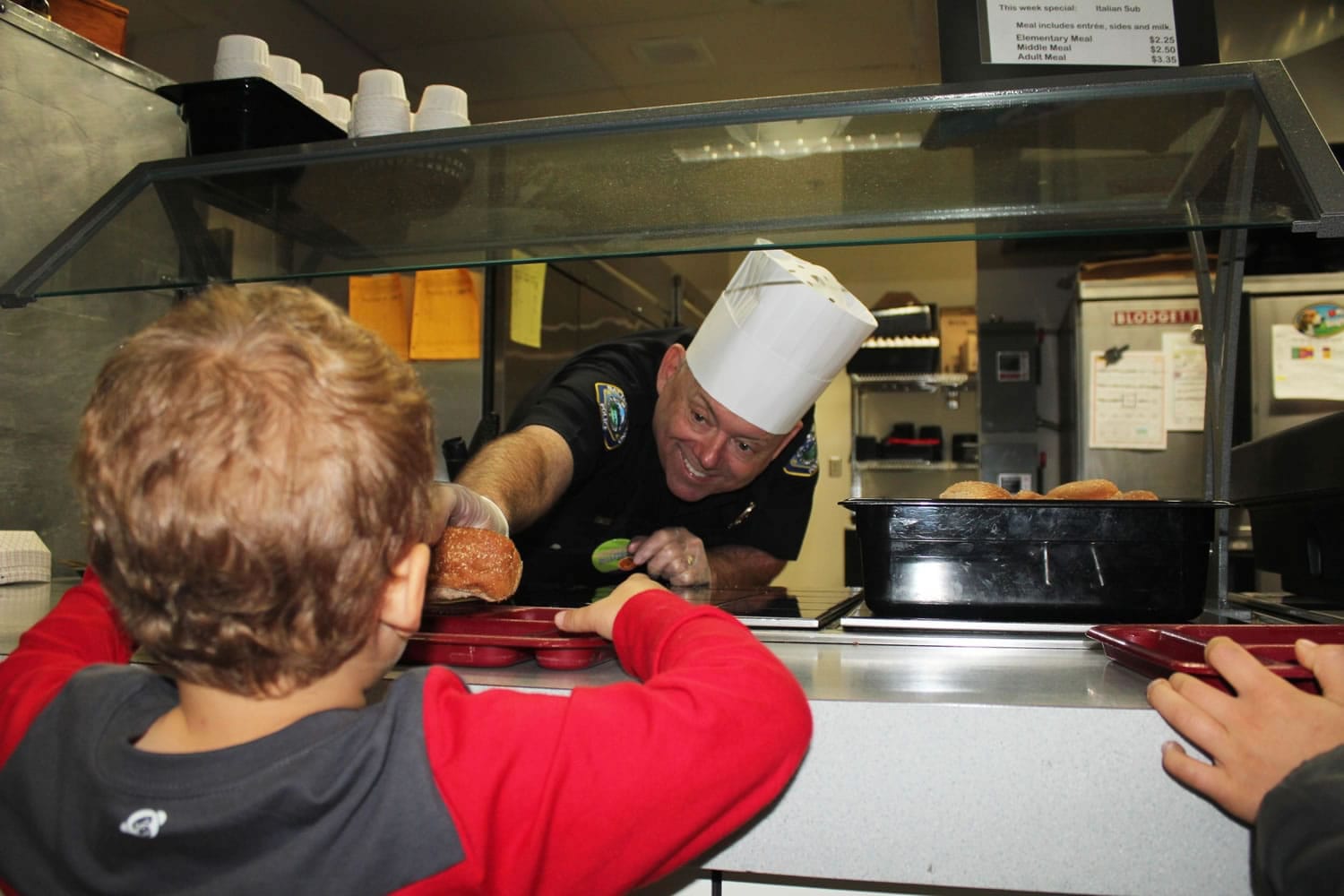Battle Ground Police Chief Bob Richardson serves hot dogs on healthful wheat buns to full-day kindergarteners in Sue Hillis class at Maple Grove K-8 School on Oct.