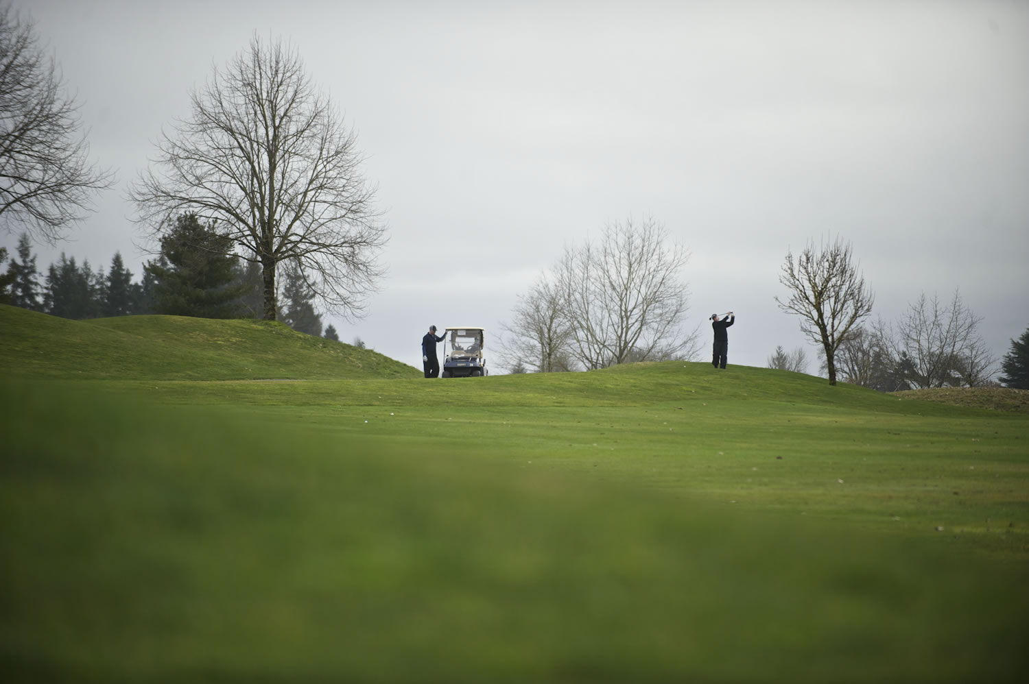 Golfers hit from the fairway on the 18th hole at the Tri-Mountain Golf Course.