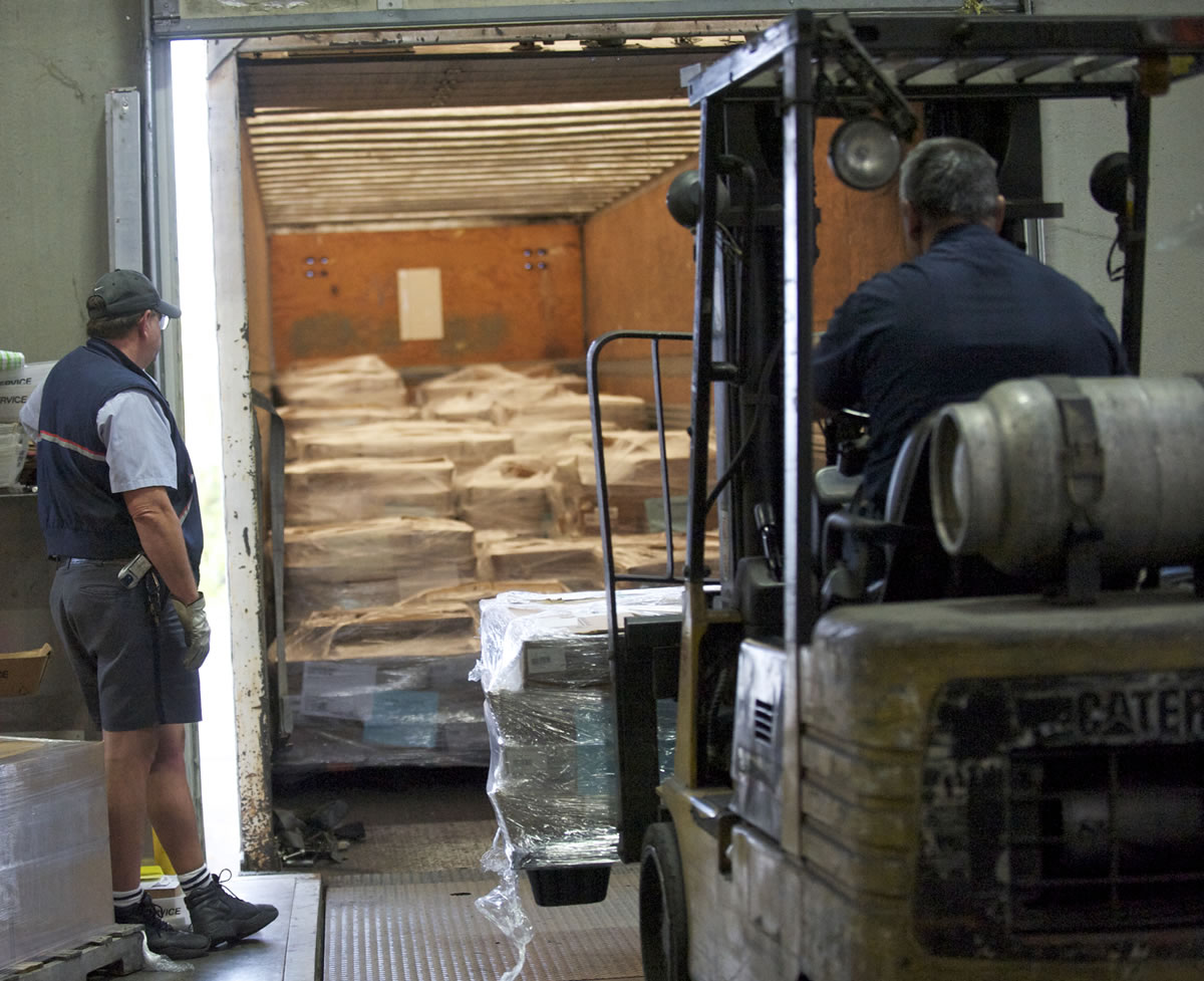 Postal Service truck driver Jim Dann, left, watches forklift operator Ricardo Ibarra load 23 pallets of Clark County ballots onto his truck at Signature Graphics in Northeast Portland on Monday. Dann took the ballots to the post office.