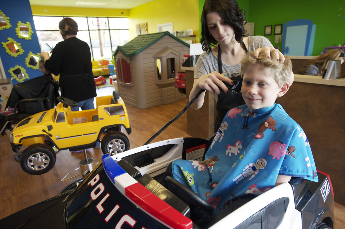 Photos by Steven Lane/The Columbian
Thomas Doerfler, 7, gets his hair cut by stylist Alli Bessette. This was Thomas' sixth haircut at the Lil' Snippers Hair Care 4 Kids and he always sits in the police car.