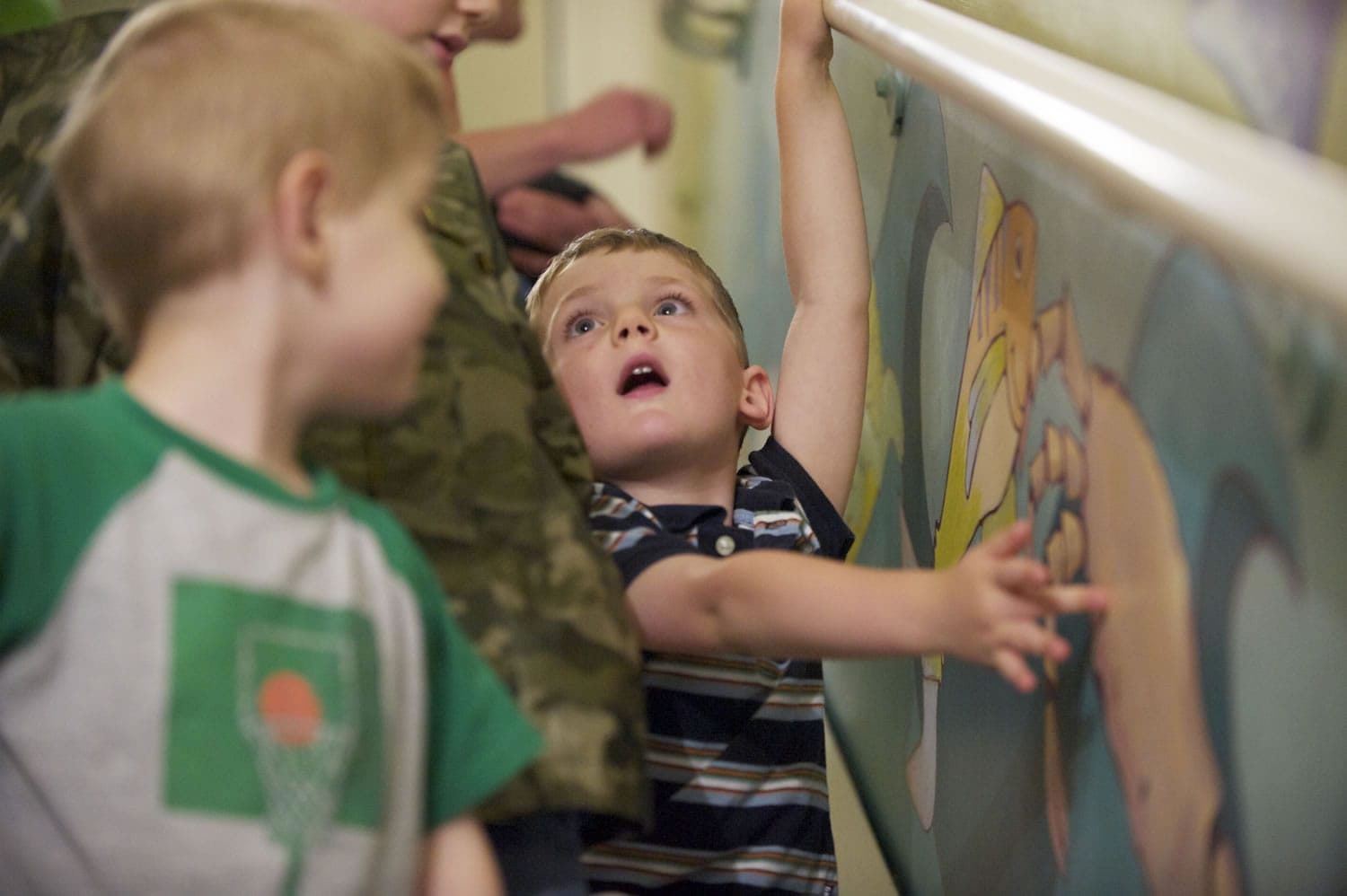 Logan Volk, 4, gets a hands-on look July 20 as Legacy Salmon Creek Hospital unveils a new mural, created by local artist Rebecca Anstine, in a stairwell used for pediatric rehab and physical therapy.