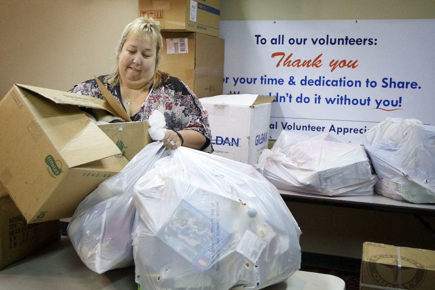 Susan Oberst, director of volunteers and community resources at Share, moves donations from a meeting room earlier this month. &quot;I do love my volunteers,&quot; she said.