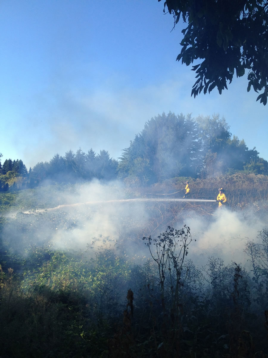 Firefighters work Monday evening to extinguish a 2-acre fire in Ridgefield.