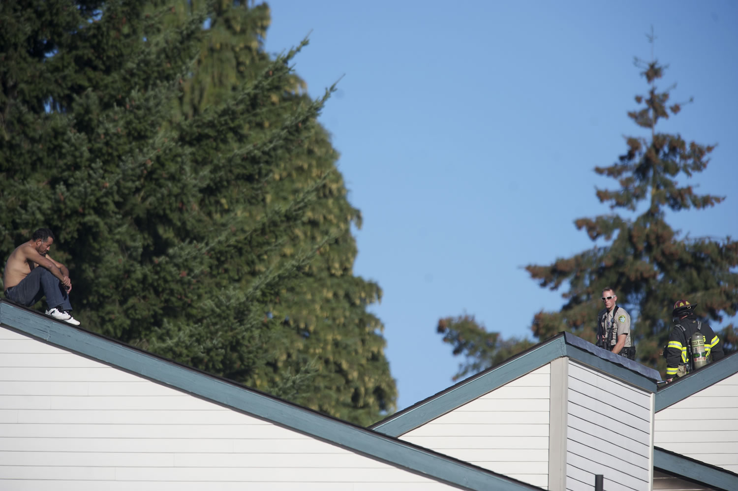 A sheriff's deputy keeps watch as a firefighter checks for hot spots the roof early into the four-hour standoff with Angel M.