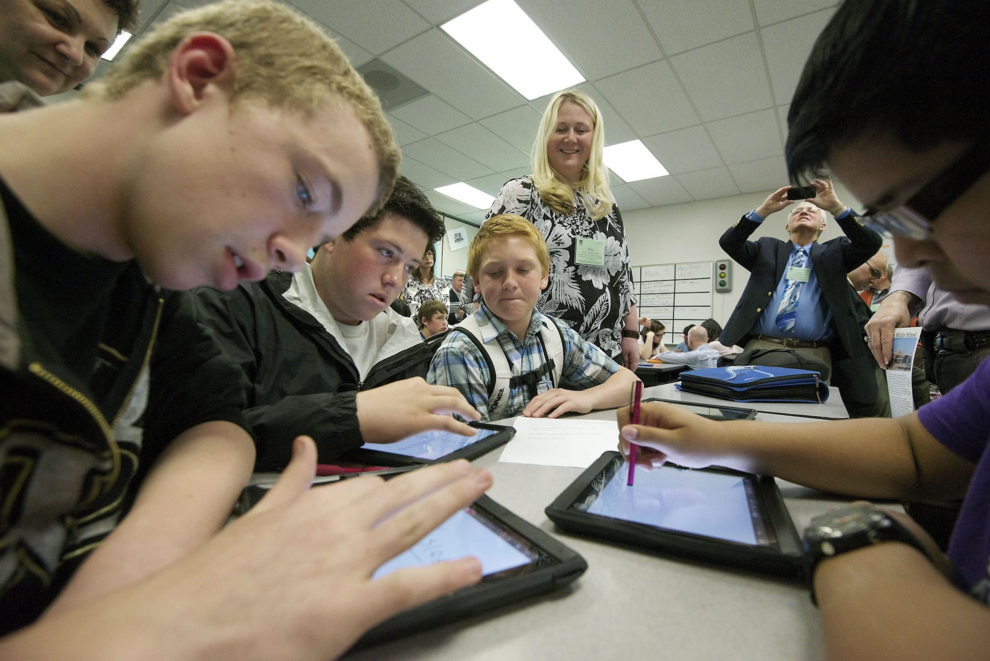 Tyler Aland, 14, from left, Jesse Schneider, 14, Teryn Siebers, 13, and Daniel Perez, 13, use iPads to solve math equations at Discovery Middle School. In the background observing, center, is Holly Palmersheim, technology professional development at Cedar Rapids Community School District in Iowa.
