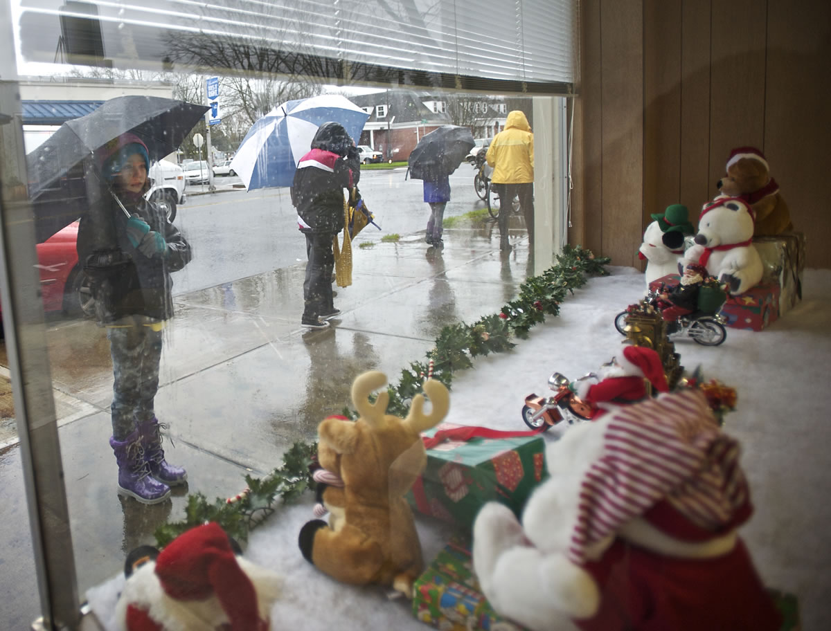 Taryn Larsen, 9, stops to look at a Santa-themed window display as the Junior Joy Team makes its way from Hough Elementary School to Esther Short Park down Main Street, Students hung ornaments embellished with positive messages on trees along the route.