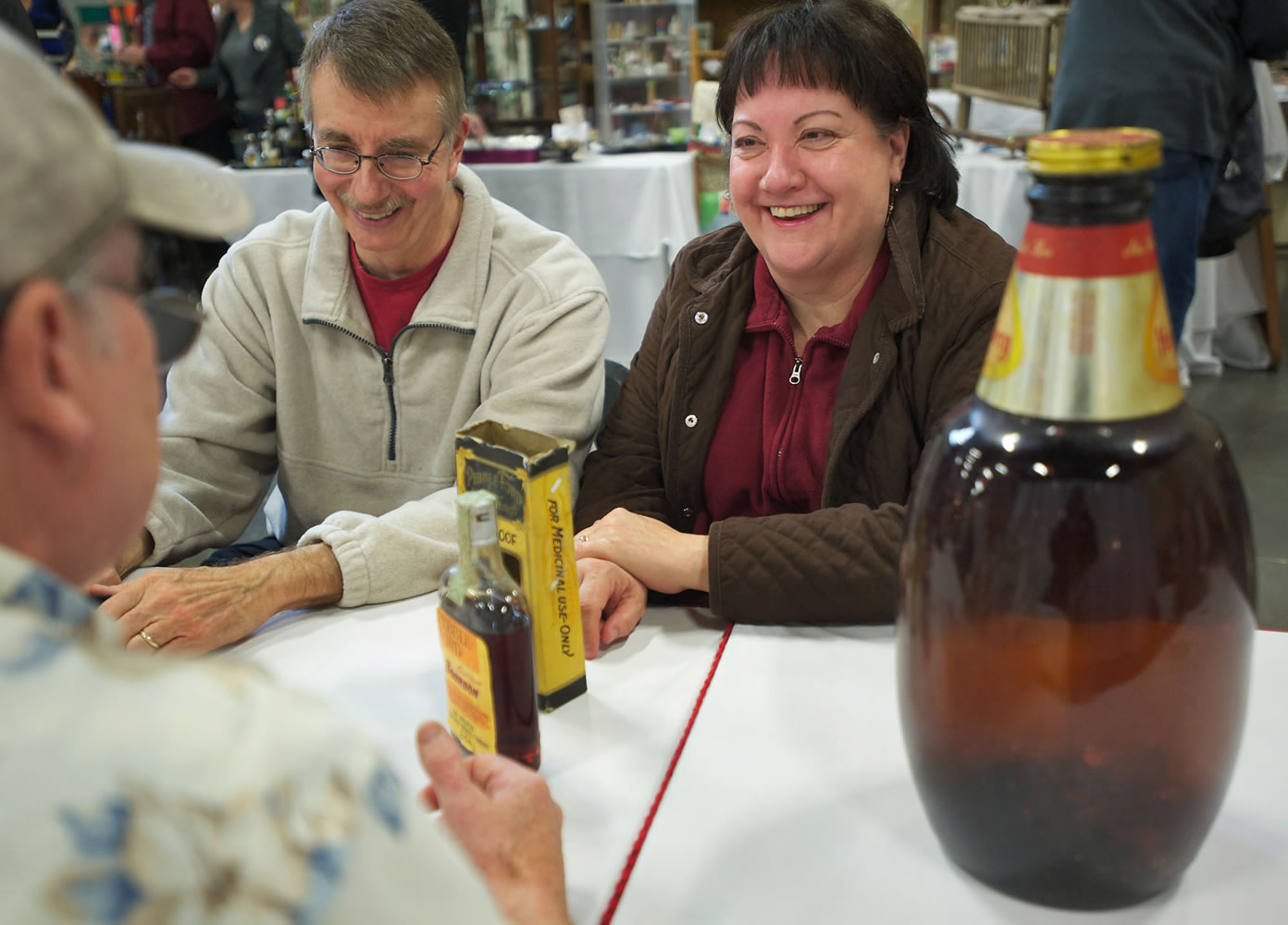 Bob and Debbie Mabry of Beaverton, Ore., talk Saturday to appraiser Randy Coe at the Clark County Antique and Collectible Show about an old bottle of bourbon they found.