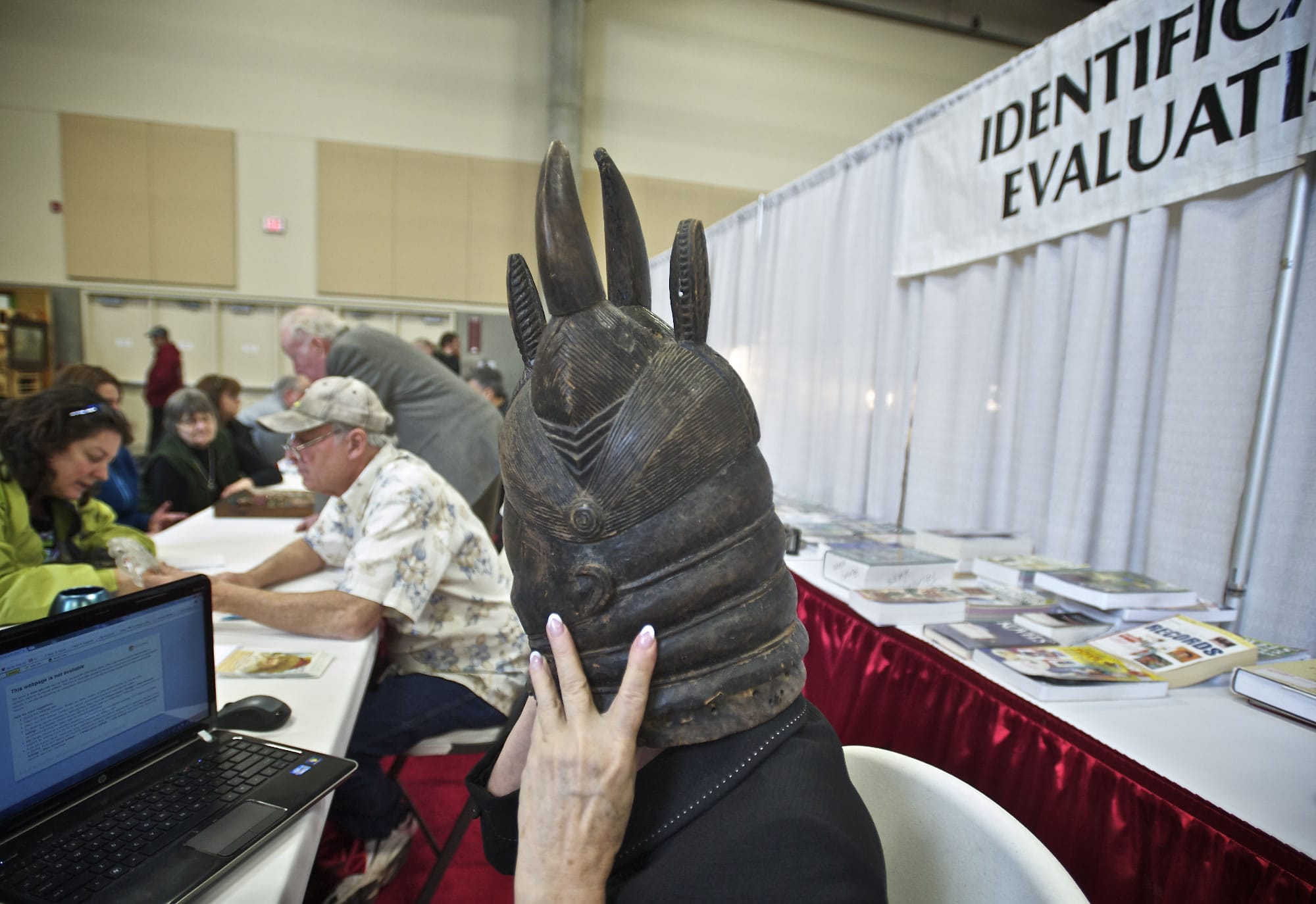 Expert appraiser Kathleen Victor tries on a wood carved mask on Saturday to get a better idea about what it was used for.