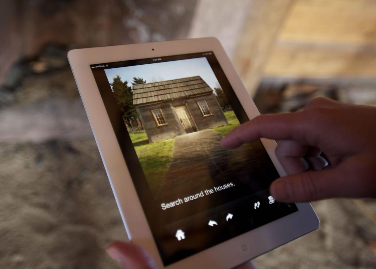Inside a replica cabin, Brett Oppegaard calls up an image on a mobile app that tells the stories of Hudson's Bay Company employees who lived at Fort Vancouver in the 1800s.